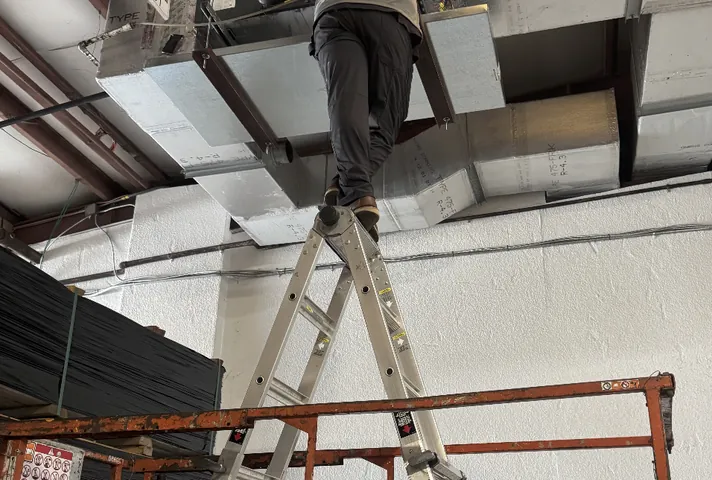 An Elite Home Solutions technician servicing ductwork in a Jacksonville commercial building