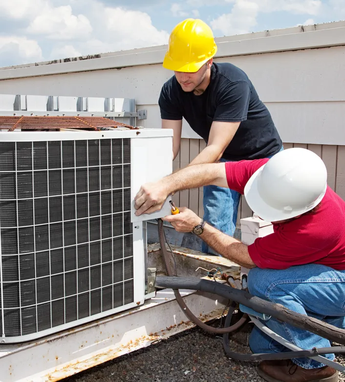 Two technicians servicing a rooftop HVAC unit