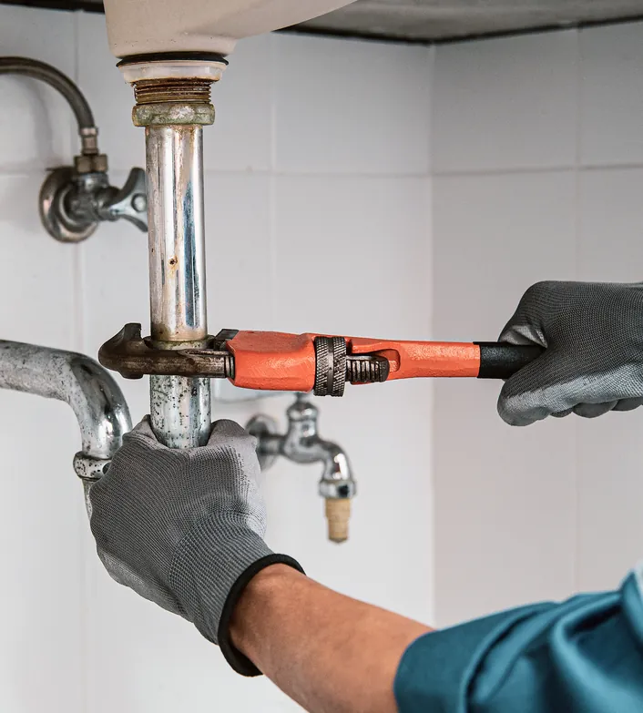Plumber tightening a supply pipe fitting with a wrench